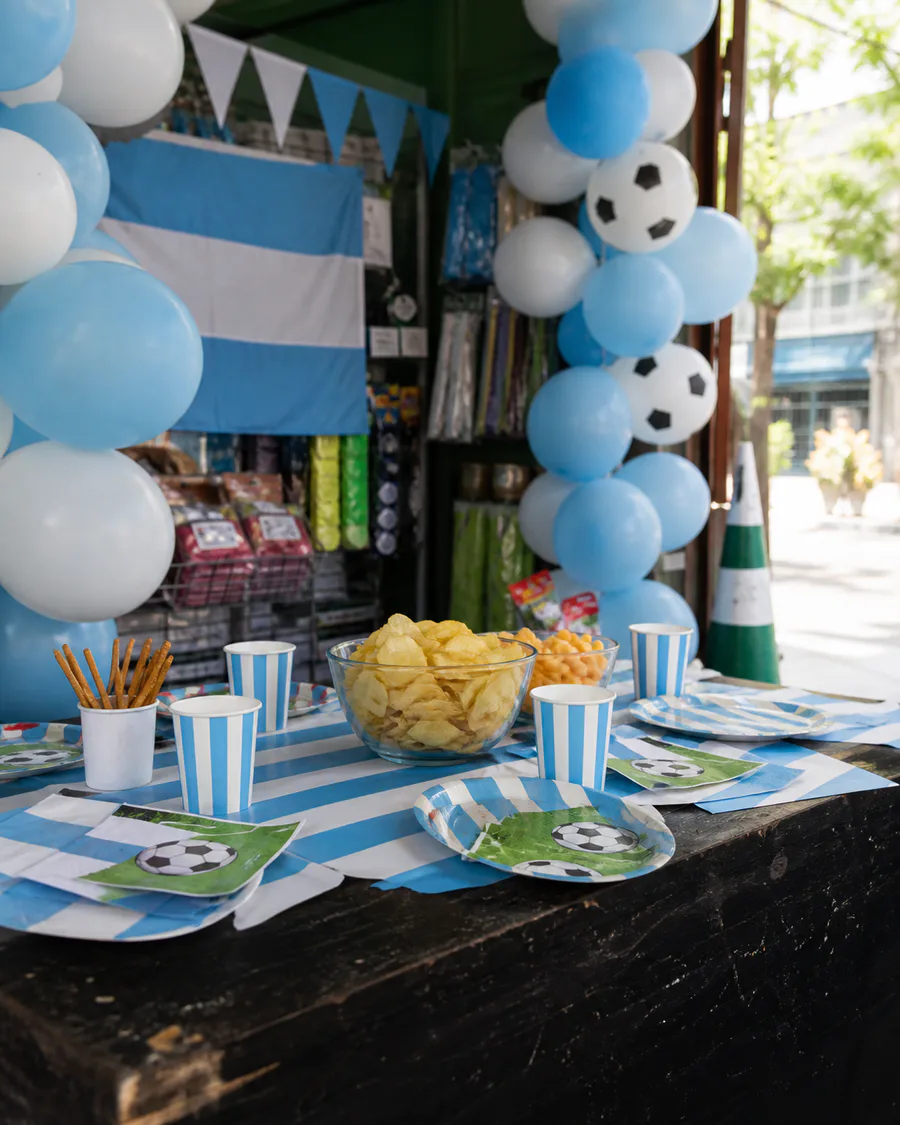 Mesa de fútbol con globos y descartables celestes y blancos